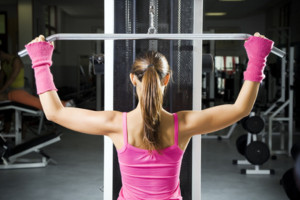 health club: girl in a gym doing weight lifting.
